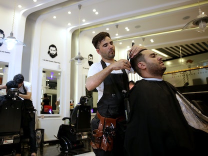 حلاق يقوم بقص شعر الزبون في مركز لتصفيف الشعر بالعاصمة الأفغانية كابول- 18 يونيو 2019 - REUTERS