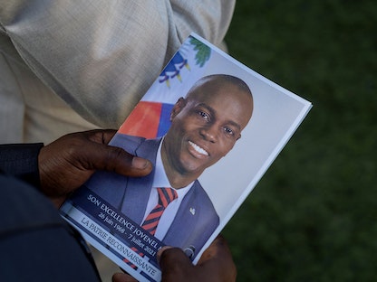 مواطن هايتي يحمل صورة الرئيس جوفينيل مويز خلال جنازته- 23 يوليو 2021 - REUTERS
