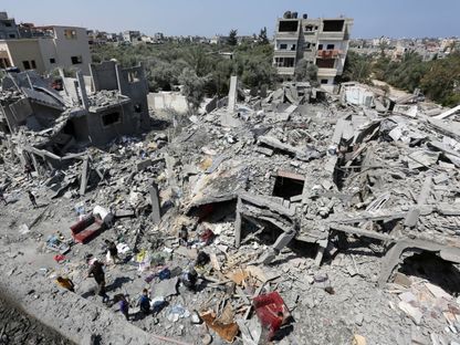 فلسطينيون يتفقدون مبانيهم المدمرة بعد الهجوم الإسرائيلي على مخيم المغازي للاجئين في مدينة غزة، 15 أبريل 2024 - AFP