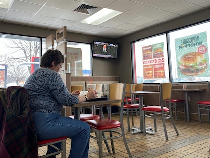 سيدة تأكل في مطعم للوجبات السريعة أثناء مشاهدة التلفزيون بمدينة دي موين عاصمة ولاية أيوا بالولايات المتحدة. 31 يناير 2020 - REUTERS