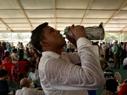 مسؤول انتخابي يشرب الماء بينما قميصه مبلل بالعرق وسط ارتفاع درجات الحرارة في أحد مراكز الانتخابات العامة بالهند. 31 مايو 2024 - REUTERS