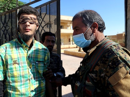 أفراد من قوات سوريا الديمقراطية يرافقون معتقلاً معصوب العينين في الرقة - REUTERS