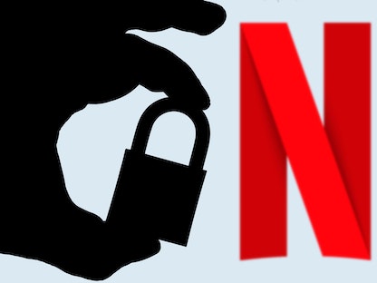 شعار شبكة نتفليكس للبث الترفيهي خلف يد مظللة تحمل قفلاً - SOPA Images/LightRocket via Gett