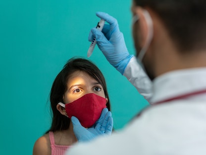 طبيب يجري فحصاً طبياً لعيني فتاة - Getty Images