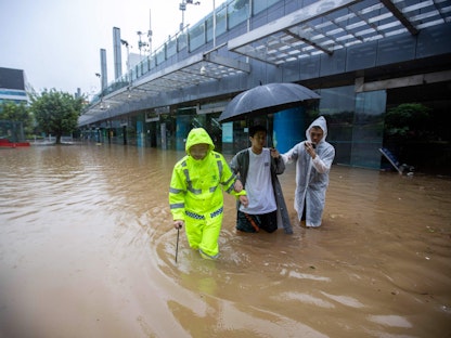 أشخاص يخوضون في مياه أمطار ناجمة عن الإعصار "هايكوي" في إقليم قوانجدونج بجنوب الصين. 8 سبتمبر 2023 - AFP