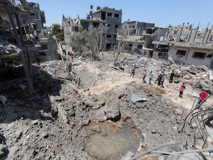 فلسطينيون يتجمعون بموقع منازل مدمرة في أعقاب القصف الإسرائيلي على غزة- 14 مايو 2021 - REUTERS