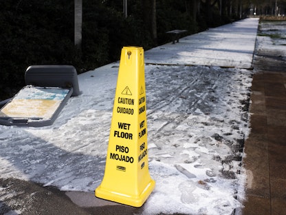 علامة تحذير على رصيف مكسو بالثلوج في هيوستن، تكساس، 15 فبراير 2021 - AFP