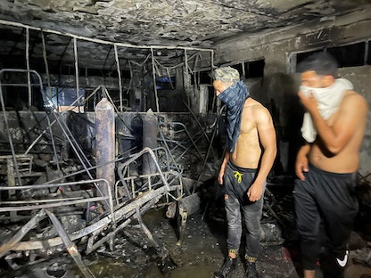عدد من الشبان يفحصون الأضرار بعد حريق مستشفى ابن الخطيب - REUTERS