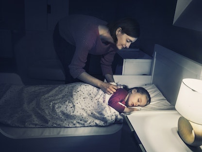 امرأة تساعد طفلتها على النوم - Getty Images