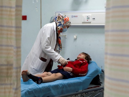 طبيبة تفحص طفلاً في مستشفى عام في عمان، الأردن. 9 ديسمبر 2021 - REUTERS