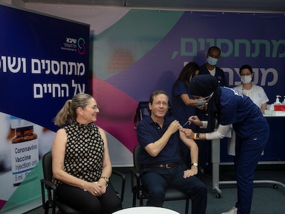 الرئيس الإسرائيلي يتسحاق هرتسوج  يتلقى جرعة ثالثة من اللقاح المضاد لكورونا، مع زوجته ميشال، في مركز طبي بتل أبيب،  30 يوليو 2021 - REUTERS