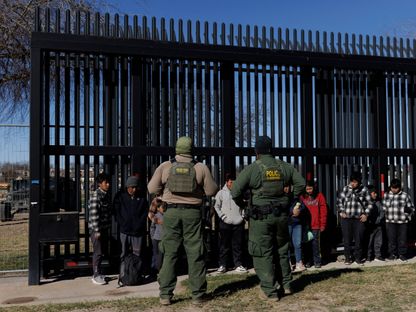 أفراد من حرس الحدود الأميركي يحرسون مهاجرين عبروا الحدود مع المكسيك في انتظار نقلهم. إيجل باس، تكساس، الولايات المتحدة. 4 فبراير 2024 - AFP