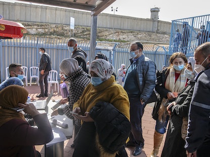 فلسطينيون في الضفة الغربية ينتظرون تلقي جرعة من لقاح "فايزر" المضاد لفيروس كورونا - AFP