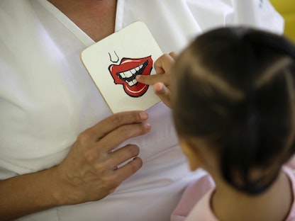 طفلة تلمس بطاقة تظهر فماً أثناء علاج النطق في مؤسسة لتنمية الأسرة بمدينة سيوداد خواريز، المكسيك. 16 أغسطس 2010 - REUTERS