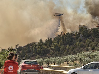مروحية تسقط المياه فوق حريق هائل قرب منطقة برودروموس على بعد 100 كيلومتر شمال شرقي العاصمة اليونانية أثينا. 21 أغسطس 2023 - AFP
