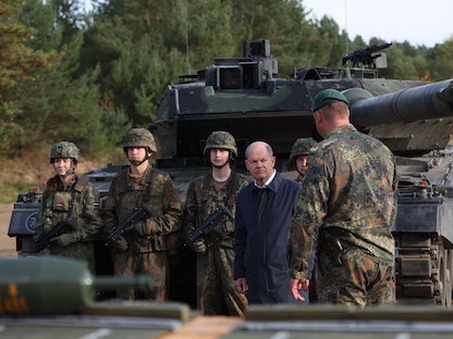 المستشار الألماني أولاف شولتز يتحدث مع جنود أمام دبابة طراز "ليوبارد 2" أثناء زيارة للجيش الألماني خلال مناورات تدريبية في أوستينهولتس شمالي ألمانيا. 17 أكتوبر 2022 - AFP