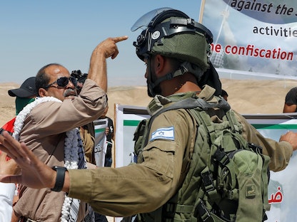 متظاهر فلسطيني يتجادل مع جندي إسرائيلي خلال احتجاج ضد بناء المستوطنات في الضفة الغربية -  4 يونيو 2021 - REUTERS