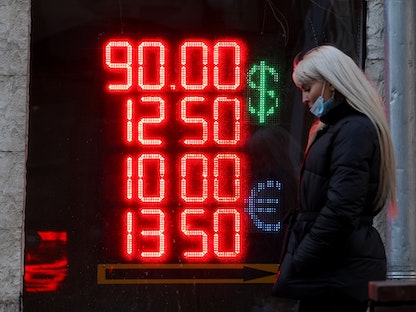 سيدة تمرّ أمام لافتة تعرض أسعار صرف العملات الأجنبية في موسكو - 28 فبراير 2022 - Bloomberg