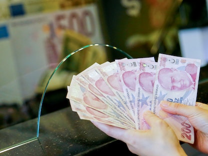 صراف يحمل أوراقاً نقدية بالليرة التركية في مكتب صرافة في أنقرة. تركيا 27 سبتمبر 2021.  - REUTERS