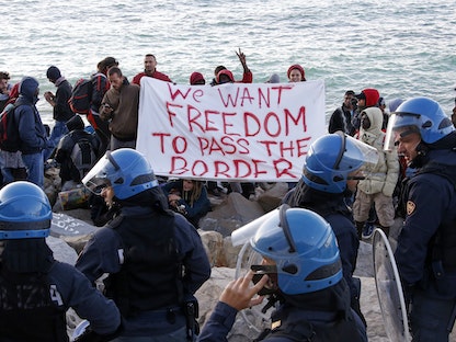 مهاجرون ونشطاء يحملون لافتة أثناء مواجهتهم الشرطة عند سانت لودوفيتش في إيطاليا. 30 سبتمبر 2015 - REUTERS