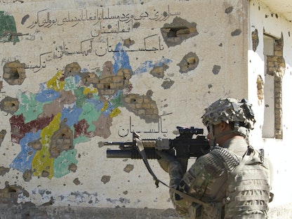 جندي أميركي يصوب سلاحه، ويقف قبالة جدارية لخريطة أفغانستان وقد شوهتها طلقات الرصاص. 9 يونيو 2012. - REUTERS