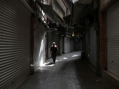 رجل يسير بجوار المتاجر المغلقة في بازار طهران بعد تشديد القيود للحد من زيادة حالات الإصابة بفيروس كوفيد 19 - 10 أبريل2021. -  REUTERS