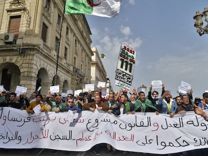 جزائريون يحملون لافتة كبيرة خلال مظاهرة مناهضة للحكومة في العاصمة الجزائر - 2 أبريل 2021 - AFP