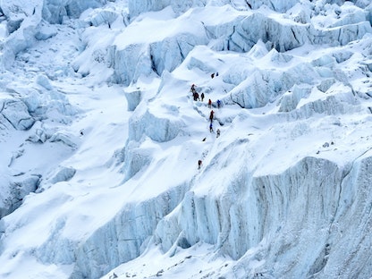 متسلقو جبال يقومون برحلة بمحاذاة نهر كاهومبو الجليدي بالقرب من معسكر قاعدة إيفرست في منطقة سولوكومبو شمال شرق العاصمة النيبالية كاتماندو. 2 مايو 2021. - AFP