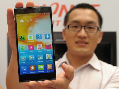 أحد مديري شركة جيوني بصحبة هاتف Gionee Elife E7 خلال حفل إطلاقه في 2014 بآرميتسار الهندية - AFP