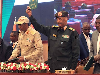 قائد الجيش السوداني عبد الفتاح البرهان يلوح بوثيقة الاتفاق الإطاري وبجواره محمد حمدان دقلو في الخرطوم. 5 ديسمبر 2022 - AFP