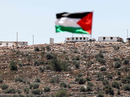 علم فلسطين يرفرف من أمام بؤرة استيطانية في قرية بيتا جنوب نابلس بالضفة الغربية- 18 يونيو 2021 - AFP