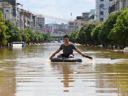 رجل يجدف عبر طريق غمرته المياه بعد هطول أمطار غزيرة في بلدة وانجبو في ينجد بمقاطعة جوانجدونج في الصين- 23 يونيو 2022.  - REUTERS