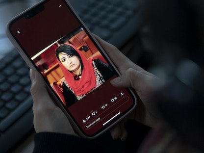 امرأة تنظر إلى صورة النائبة الأفغانية السابقة مُرسل نبي زاده على هاتف محمول في العاصمة كابول. 15 يناير 2023 - AFP