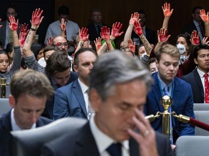 محتجون ضد حرب إسرائيل على غزة يرفعون أياديهم خلف وزير الخارجية الأمريكي أنتوني بلينكن، خلال جلسة استماع بمجلس الشيوخ، واشنطن. 31 أكتوبر 2023 - Bloomberg - Bloomberg