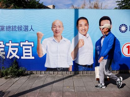 رجل يمر أمام إعلان حملة لهو يو إيه، المرشح للرئاسة التايوانية، من حزب المعارضة الرئيسي الكومينتانج في مدينة تايبيه، تايوان في 2 يناير 2024 - Reuters