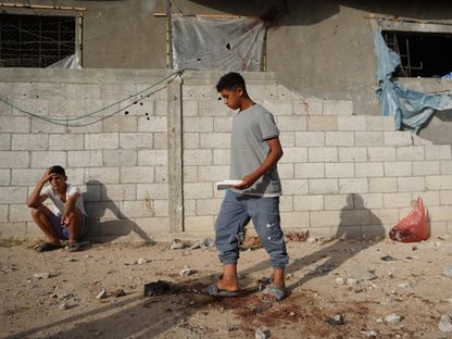 فلسطينيان يتفقدان الأضرار التي أعقبت الغارات الإسرائيلية على بلدة الزوايدة في محافظة دير البلح وسط غزة. 22 مايو 2024 - AFP