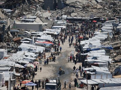 فلسطينيون في سوق بالقرب من أنقاض المنازل في مخيم جباليا للاجئين، شمال قطاع غزة. 8 مايو 2025 - Reuters