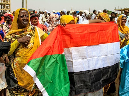 نساء يرفعن العلم الوطني السوداني بينما يتجمع الناس للاحتجاج خارج بعثة الأمم المتحدة في العاصمة السودانية الخرطوم، 1 يونيو 2022. - AFP