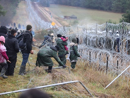 مهاجرون يتجمعون بالقرب من سياج أسلاك شائكة بمنطقة غرودنو في بيلاروسيا، في محاولة لعبور الحدود مع بولندا  - 8 نوفمبر 2021 - via REUTERS