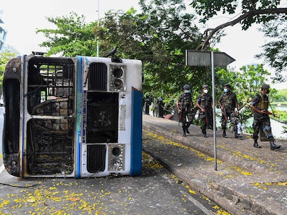 جنود يمشون أمام حافلة تم حرقها خلال مظاهرات ضد الحكومة بسبب الأزمة الاقتصادية في كولومبو عاصمة سريلانكا في 11 مايو 2022 - AFP