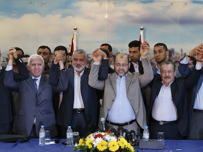 قيادات حركتي فتح وحماس يرفعون أيديهم بعد إعلان اتفاق المصالحة الفلسطينية في مدينة غزة - 23 إبريل 2014  - REUTERS