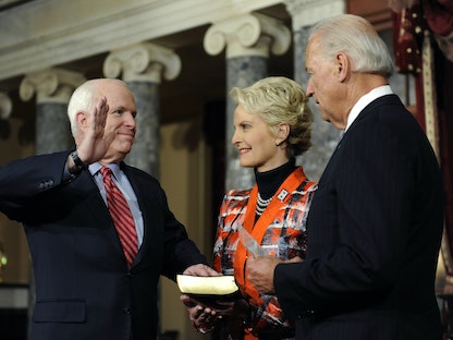 عضو مجلس الشيوخ السابق جون ماكين، يؤدي اليمين أمام الرئيس الأميركي جو بايدن، عندما كان يشغل منصب نائب الرئيس، إلى جانب زوجته سيندي ماكين، في مبنى الكابيتول -  واشنطن - 5 يناير 2011 - REUTERS