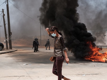 امرأة تسير بجوار إطارات محترقة في العاصمة السنغالية داكار. 1 يونيو 2023 - AFP