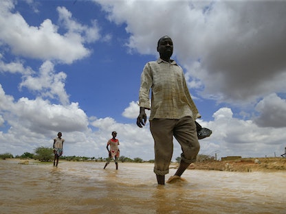 سودانيون يسيرون عبر مياه الفيضانات في بلدة العسيلات جنوب العاصمة الخرطوم، 6 أغسطس 2020 - AFP