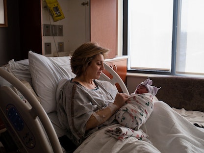 أم تحمل طفلها بعد ولادته في ولاية ميشيجان الأميركية. 1 فبراير 2022 - REUTERS