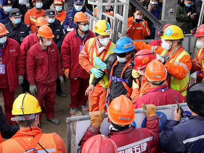 عناصر الإغاثة يسوقون رجلاً تم إنقاذه من بين عمال المنجم العالقين تحت الأرض - AFP