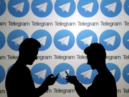 رجلان يقفان مع هواتف ذكية أمام شاشة تظهر شعارات Telegram في البوسنة والهرسك. 18 نوفمبر 2015 - REUTERS