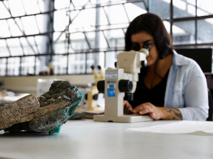 باحثة تنظر من خلال مجهر في "الصخور البلاستيكية"، التي عثر عليها في جزيرة ترينداد في ولاية إسبيريتو سانتو ، في مختبر جامعة بارانا الفيدرالية، البرازيل. 7 مارس 2023 - REUTERS
