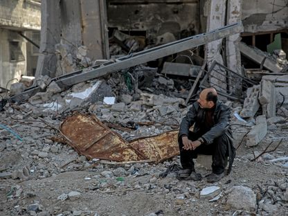 فلسطيني يجلس وسط أنقاض مبنى دمره الجيش الإسرائيلي في قطاع غزة. 26 فبراير 2024 - AFP