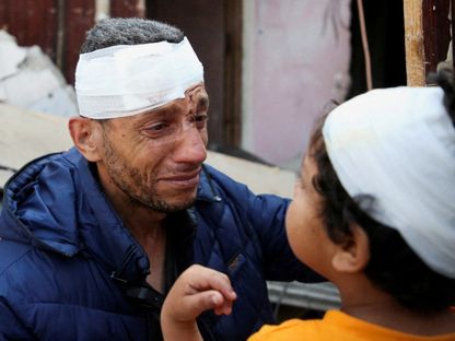 رجل فلسطيني يواسي ابنه بعد إصابتهما في غارة إسرائيلية على منزل وسط مدينة رفح، بجنوب قطاع غزة. 1 مايو 2024 - REUTERS